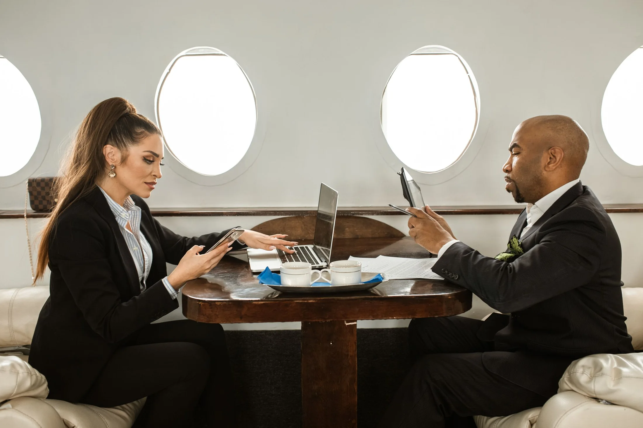 Two business travellers seated inside a modern private jet cabin
