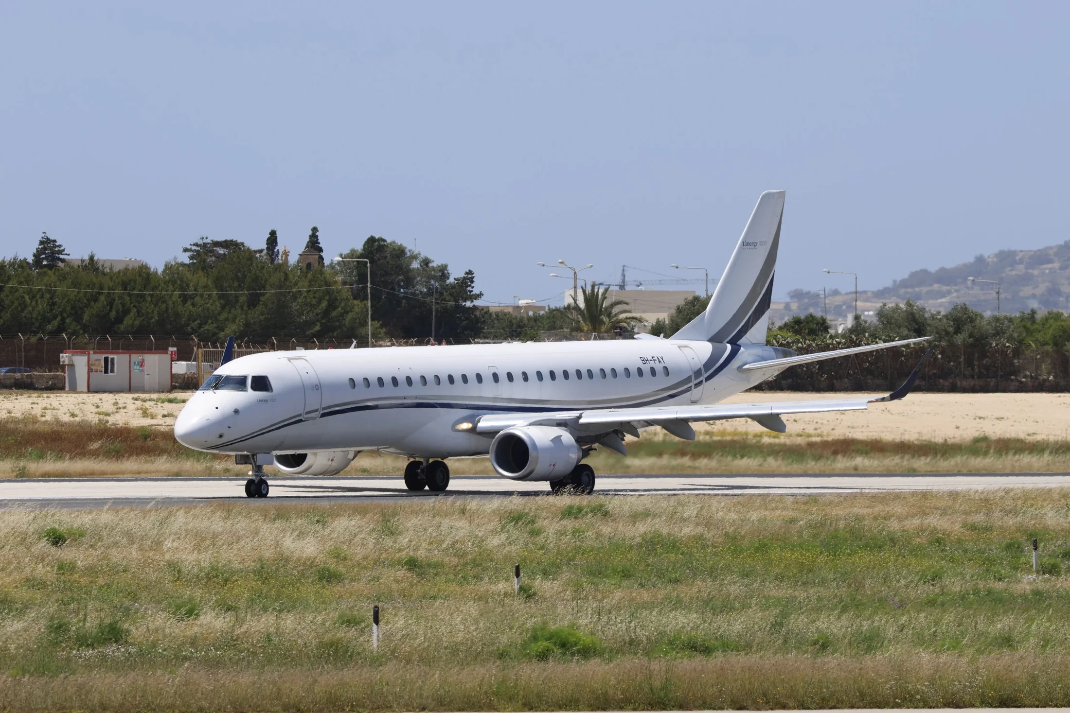 Modern executive group charter aircraft taxiing on a bright runway