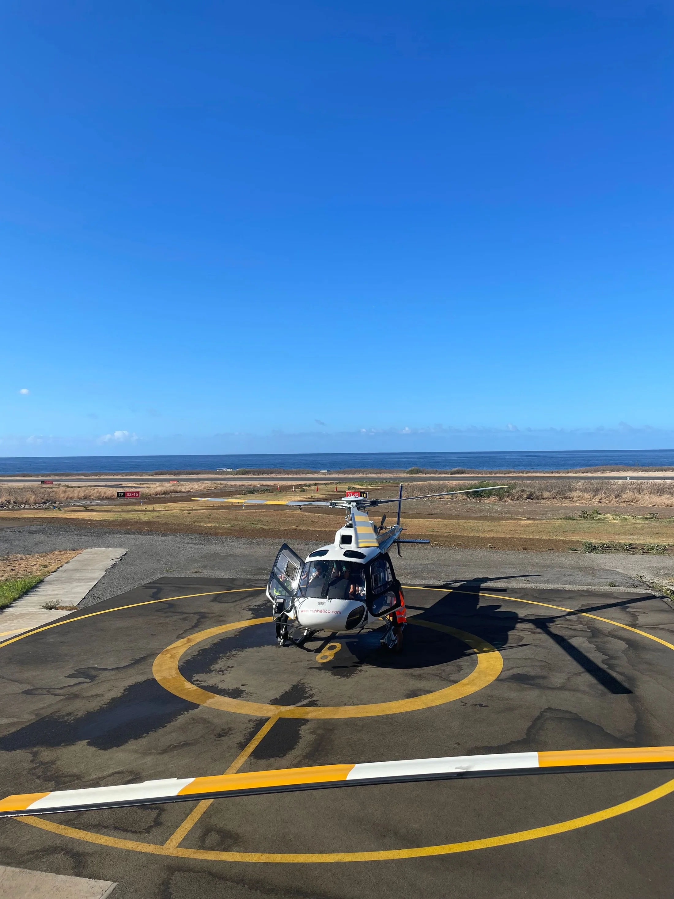 Modern helicopter on a coastal helipad beneath a clear blue sky