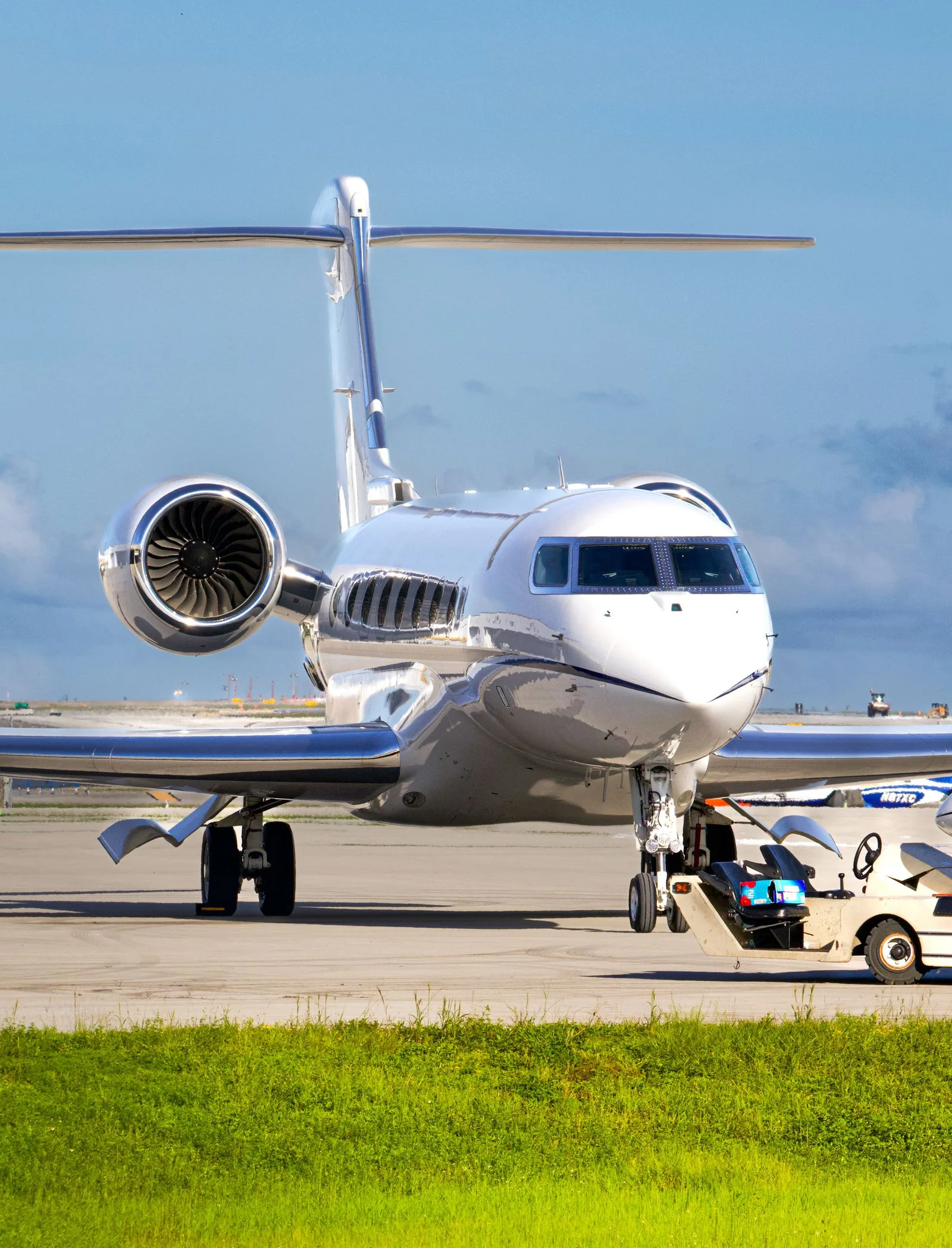 Modern private jet on a clean airport tarmac beneath a bright blue sky