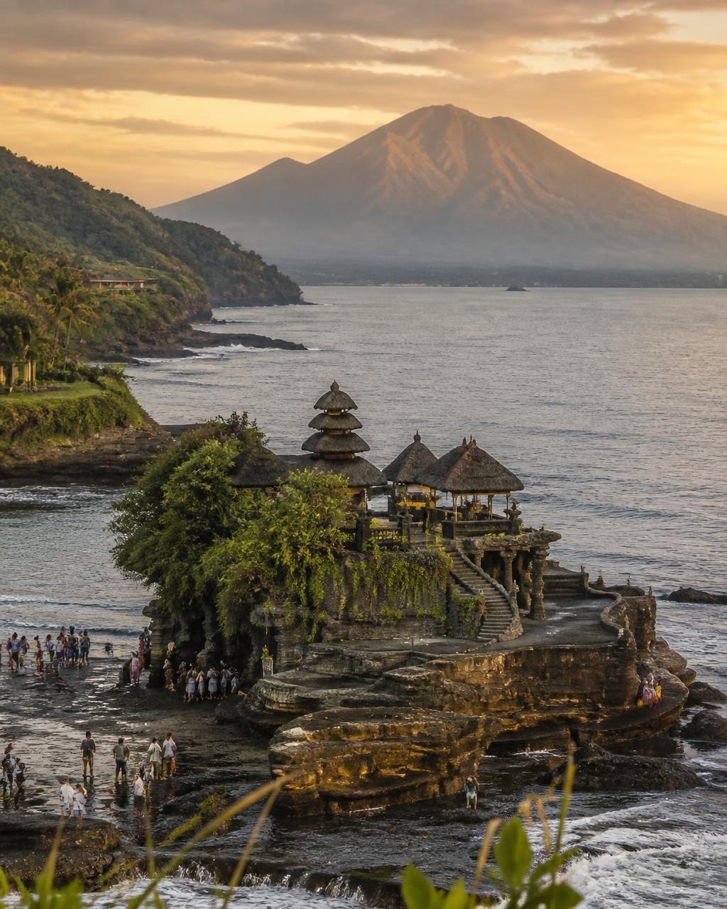 Balinese sea temple on a rocky outcrop with a volcano behind at sunset
