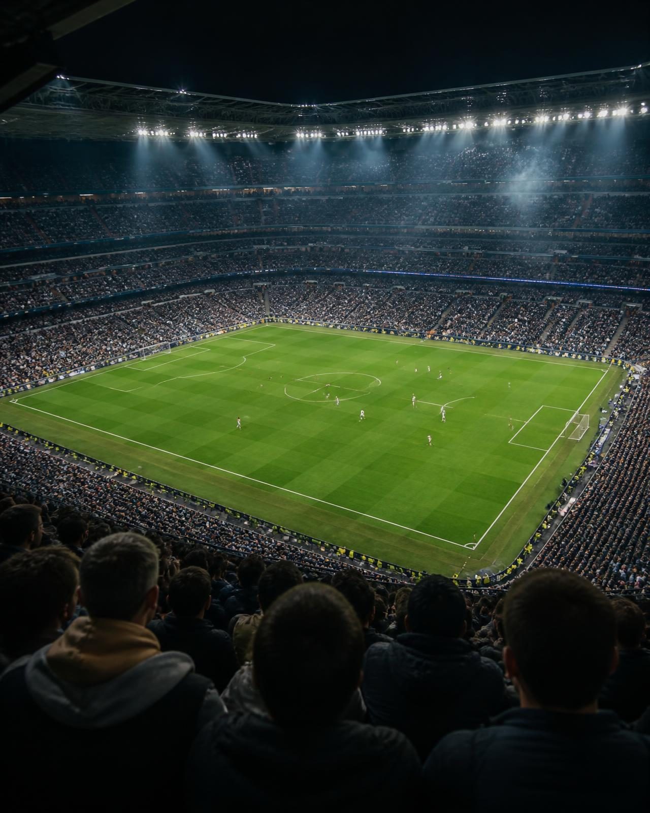 A full football stadium seen from the upper stand at night