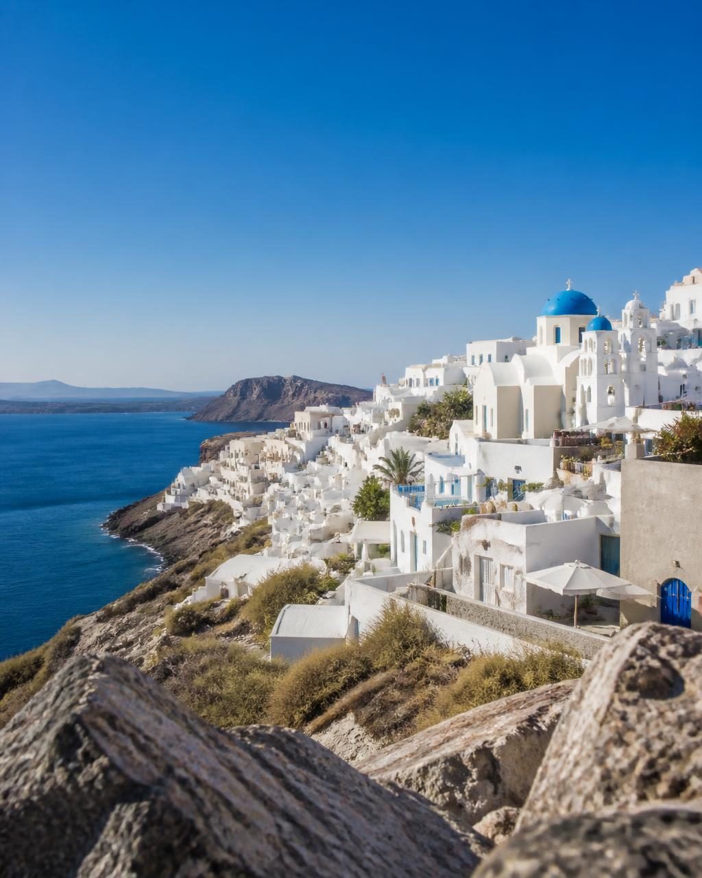 Whitewashed Cycladic village with blue domes above the deep Aegean