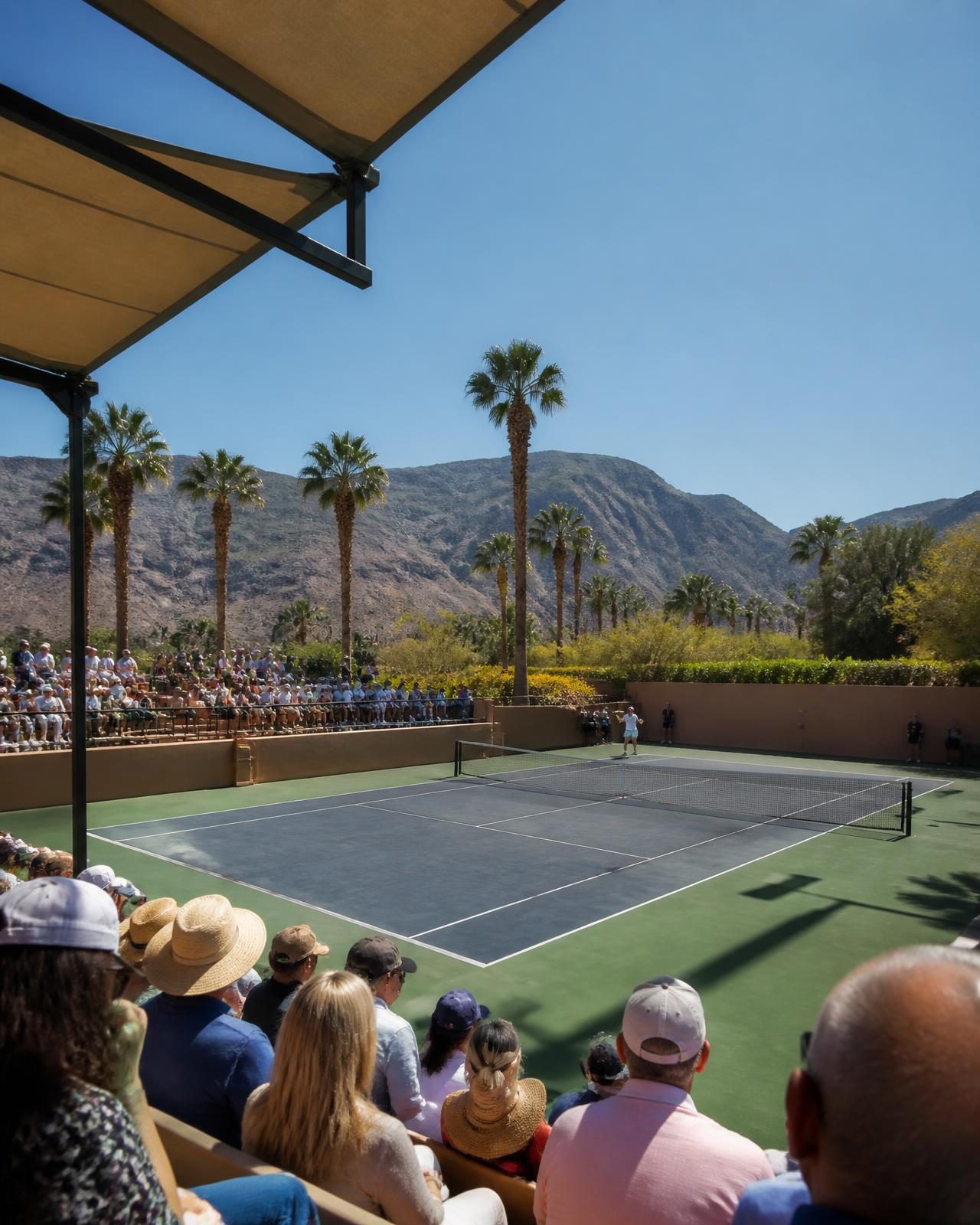 A desert tennis court with palm trees and arid mountains behind