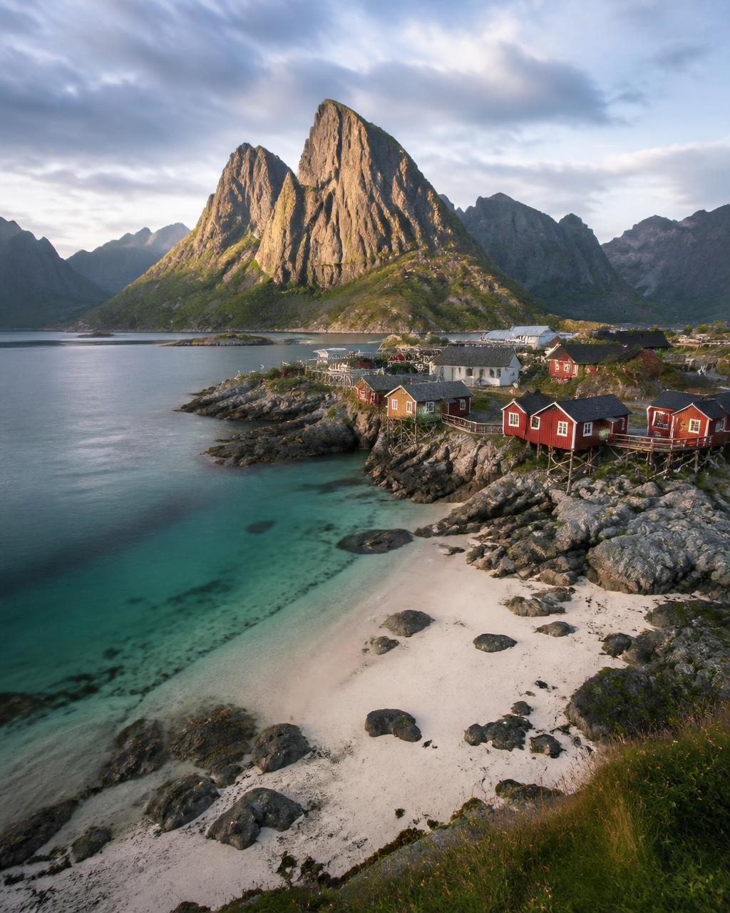 Granite peaks above a red fishing village and clear cold water in the Lofoten Islands