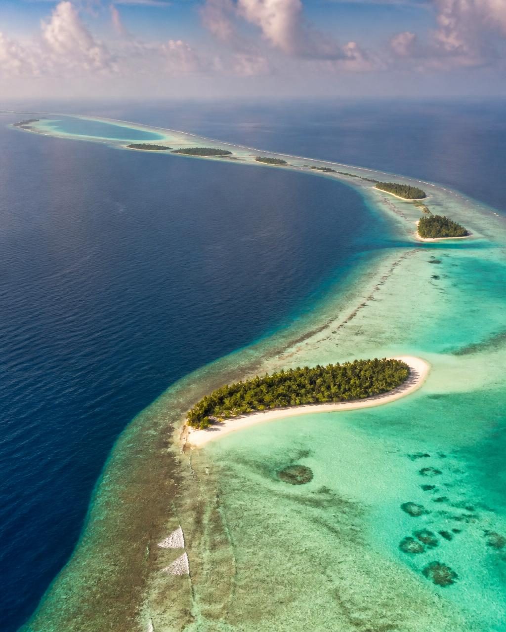 Aerial view of a Maldivian atoll rim with a sandbank and pale lagoon
