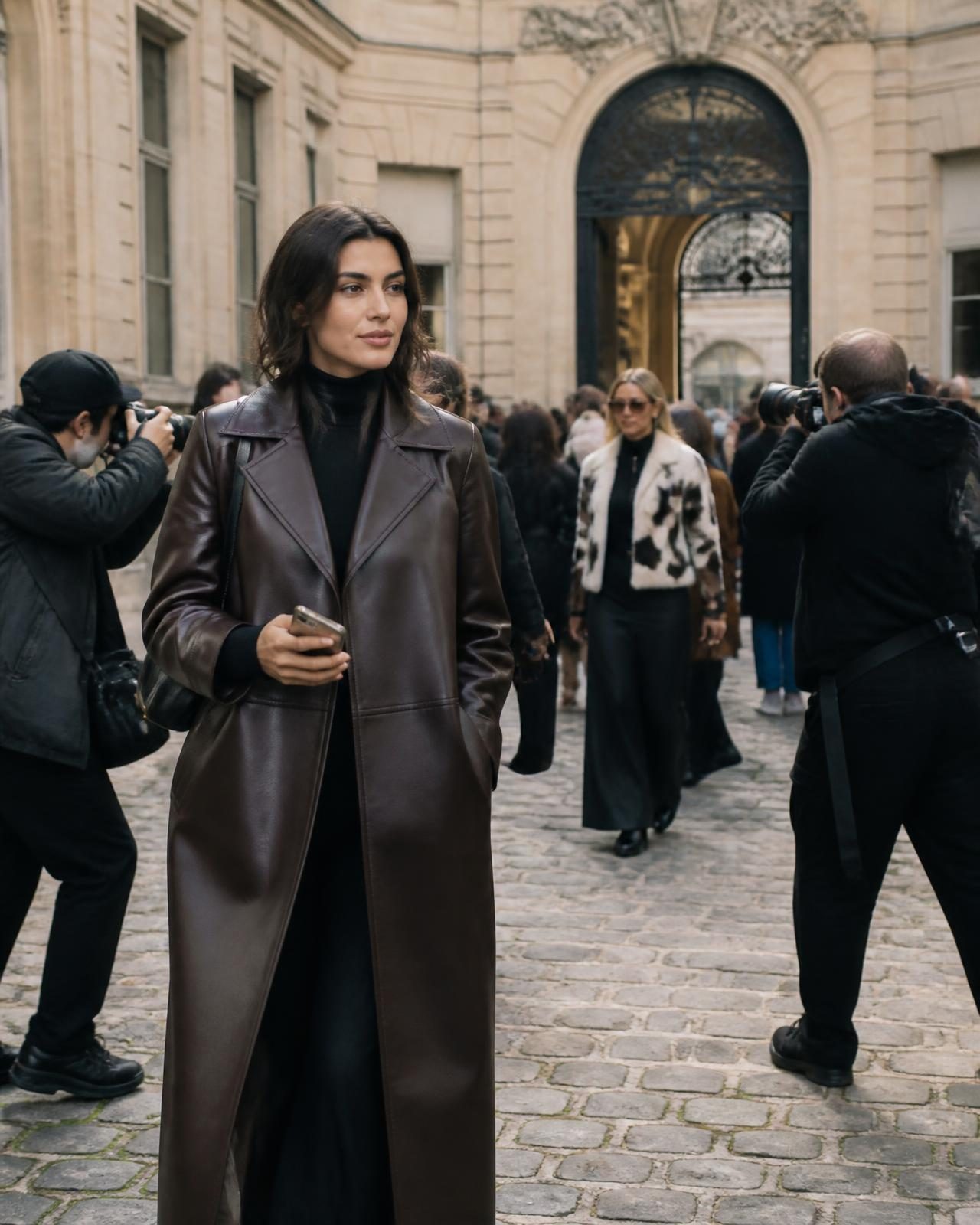 Elegantly dressed guests and photographers in a Parisian courtyard