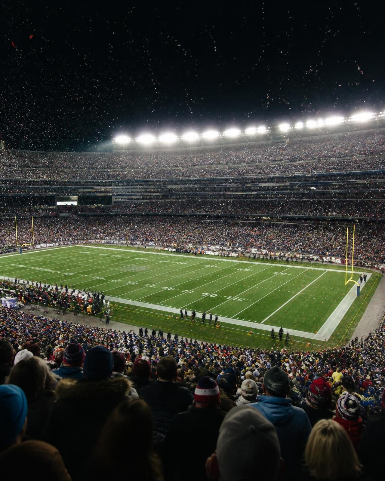 A packed American football stadium under floodlights on a final night