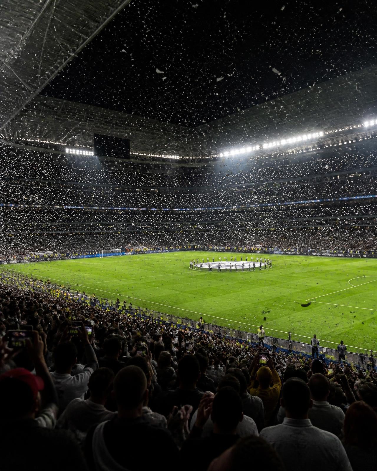Confetti falling over a floodlit football pitch at the end of a final